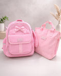 Two pink bags with a bow on a light gray surface.